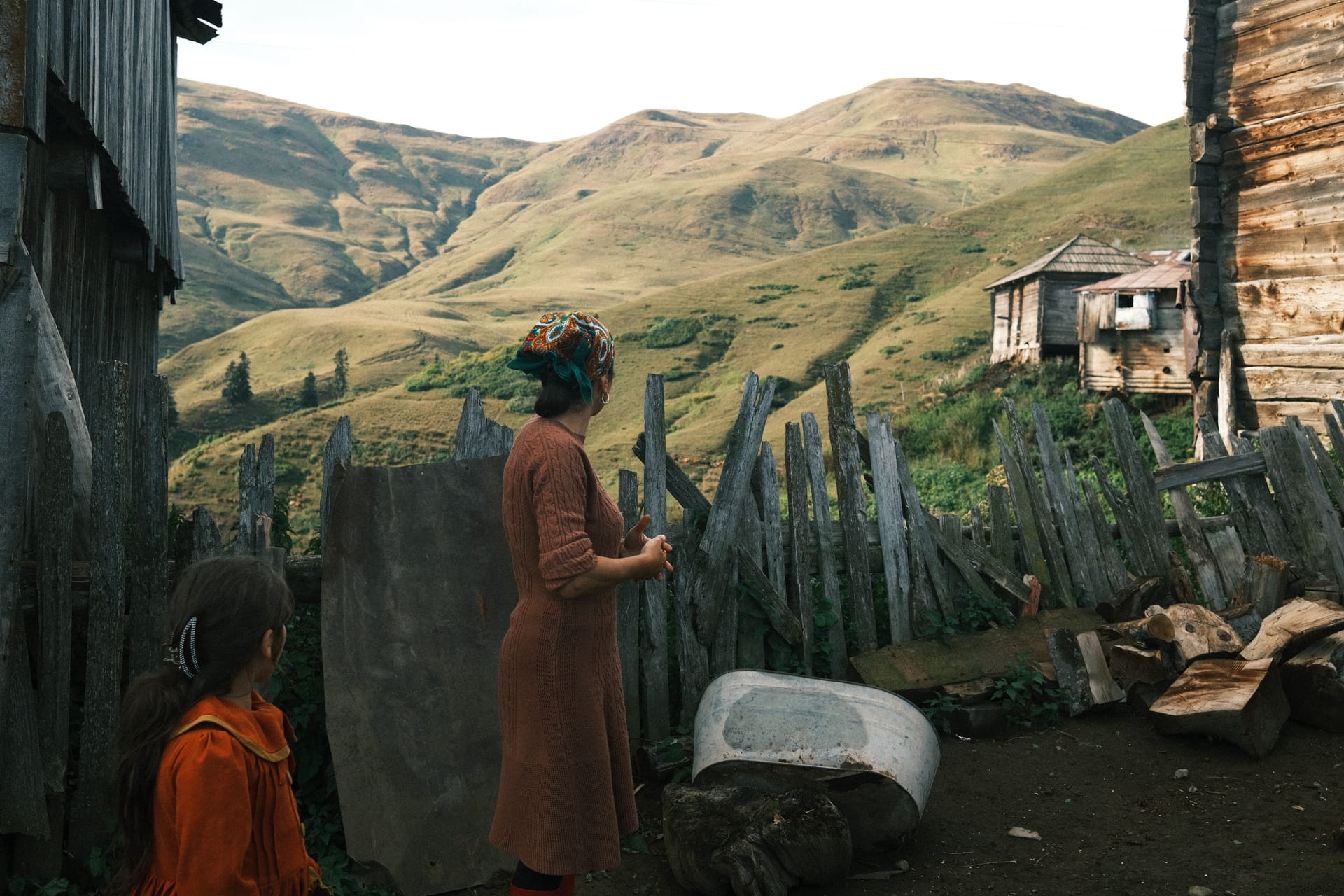 A mother and daughter in traditional dress overlooking a mountain village in Adjara