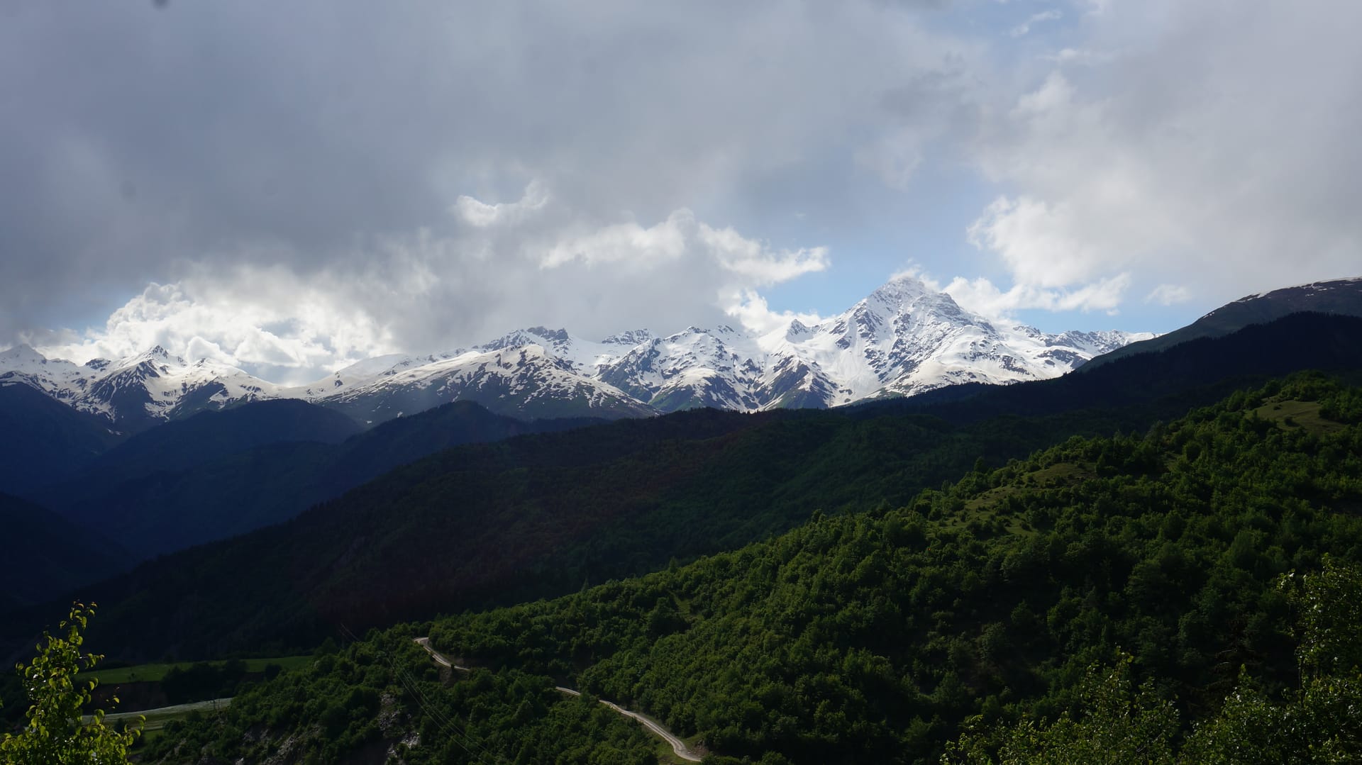 Forested mountains and snow-capped peaks along a Svaneti highland road